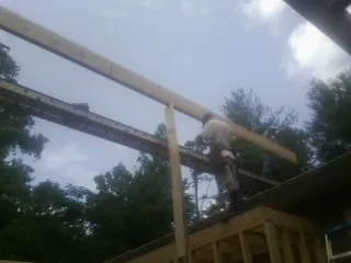 Carpenter setting a ridge beam over a new addition frame — Ice Dam Removal by Roofing Brothers in Mocksville