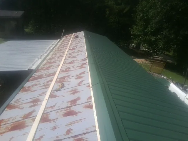 Old rusted panels beside newly installed green metal roofing — Wind Damage Roof Repair by Roofing Brothers in Mocksville