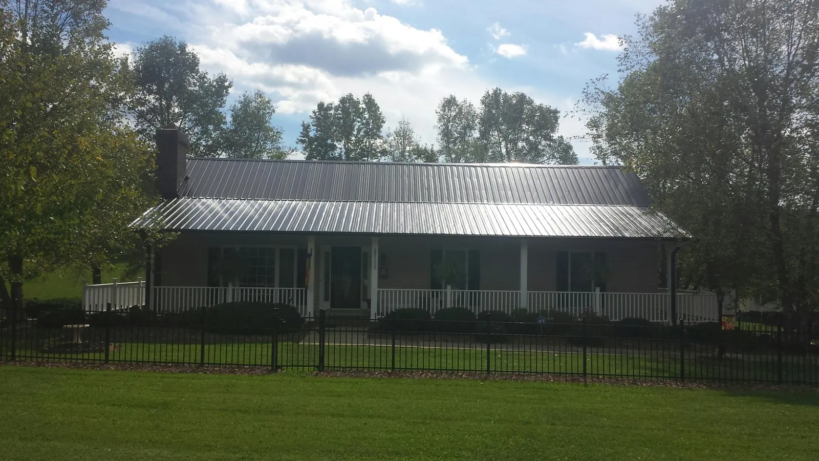 Gray metal roof on a brick ranch with a full width front porch — Gutter Guard Installation work by our crew in Mocksville