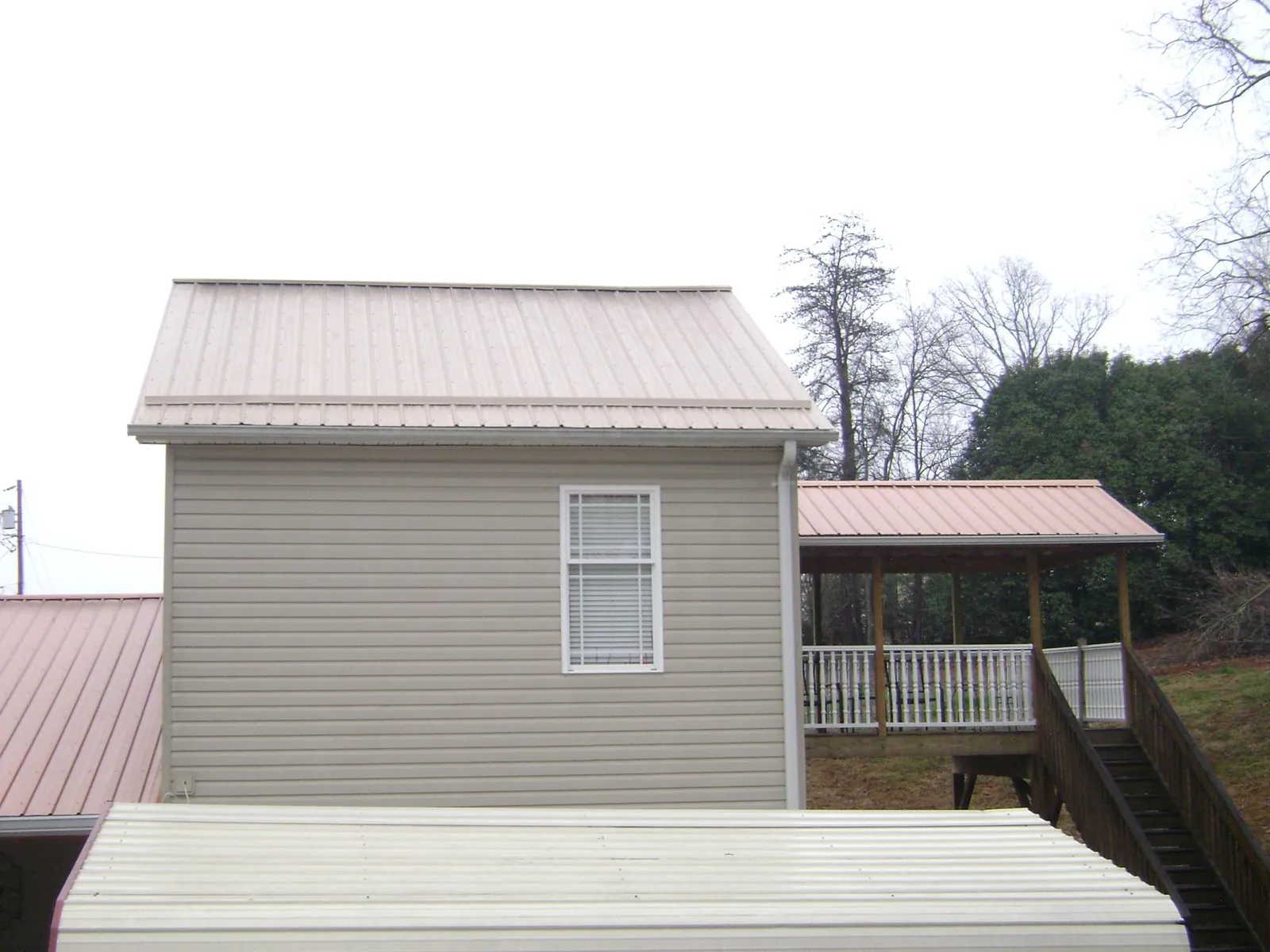 Tan metal roofs on a two story addition and attached porch, from a Roof Replacement job in Mocksville