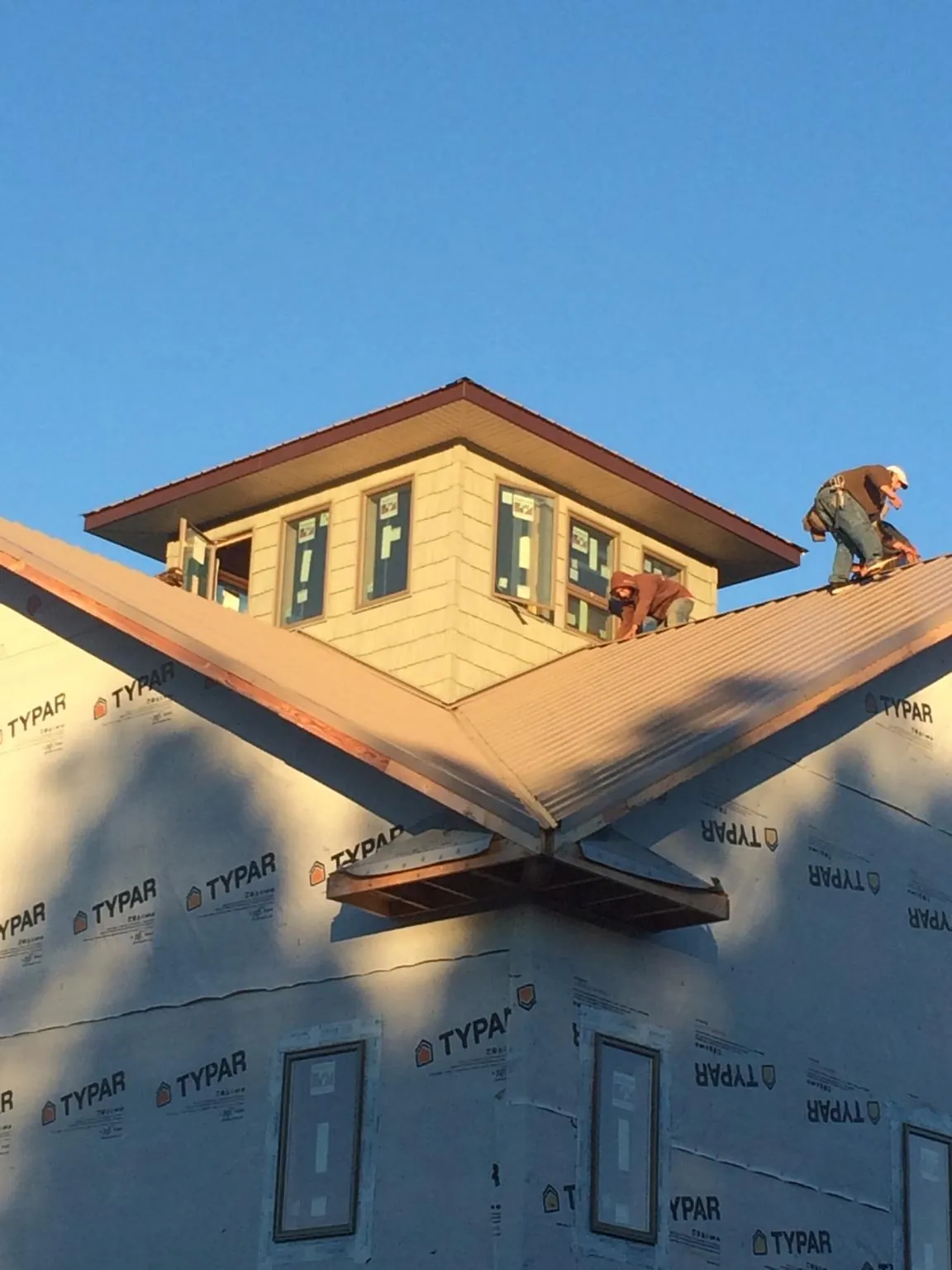 Roofers working around a rooftop cupola on a new metal roof at sunset — Roof Waterproofing in Mocksville by Roofing Brothers